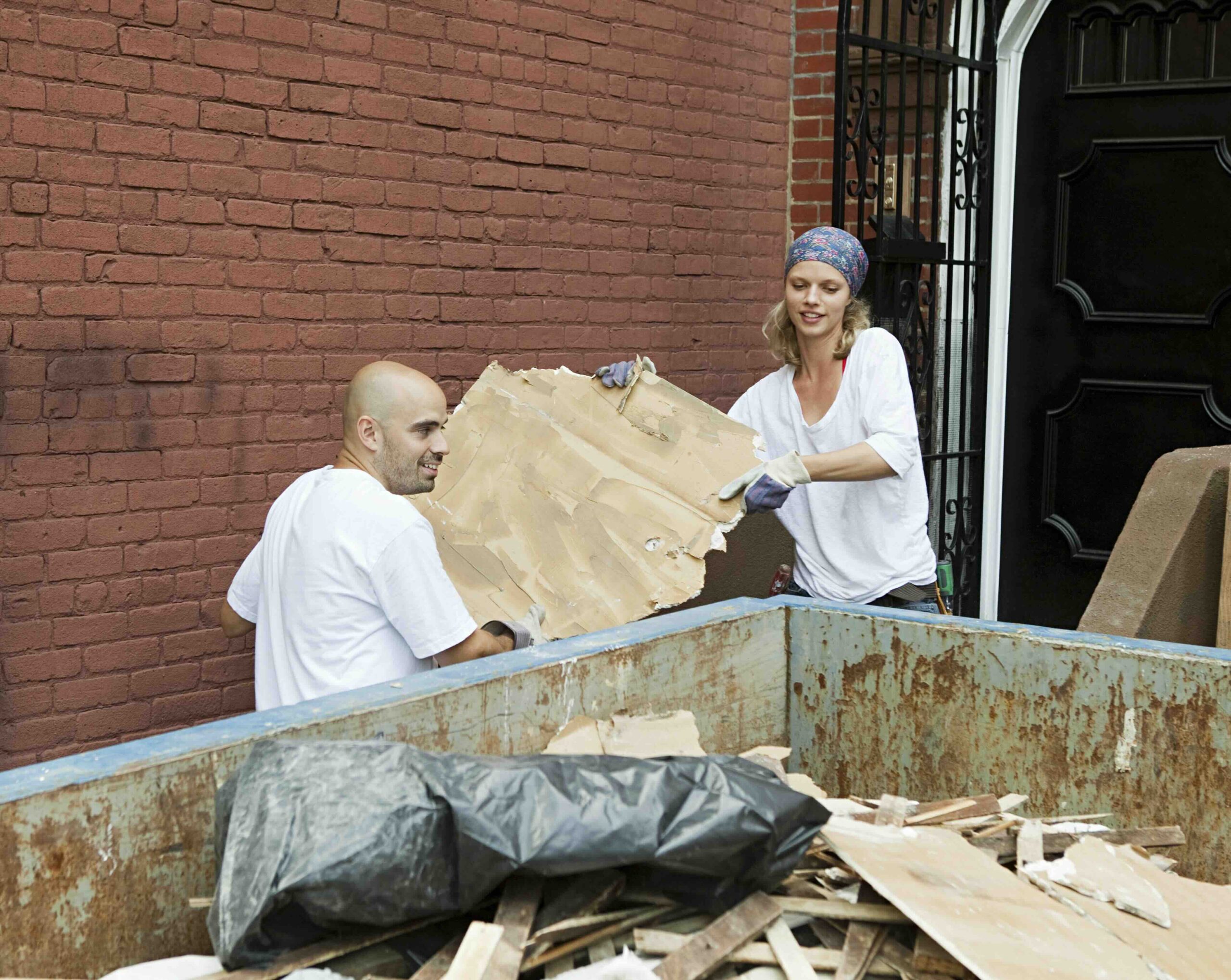 Photo of a couple using a dumpster during a home renovation project.